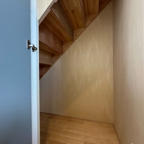 階段下のデッドスペースを利用した収納です。  低い所には新聞・雑誌等資源ゴミに出すまで保管しておいたり、高さがある所にはコンセント付きなのでコードレス掃除機を充電しながら収納できます。