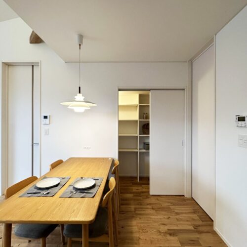 キッチンの反対側には家族で囲むダイニングテーブル。  奥の扉はパントリーに繋がります。  可動式の造作棚を取り付け、ストック品も余裕の収納！