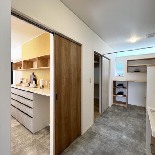 キッチン奥の扉を進むと水回りへ。  （フロアタイル：サンゲツ IS-1025）  奥の引戸は、WIC→寝室へと続いています。  そうなんです、主寝室→キッチン→水回り→WIC→主寝室と回遊動線の完成です～！