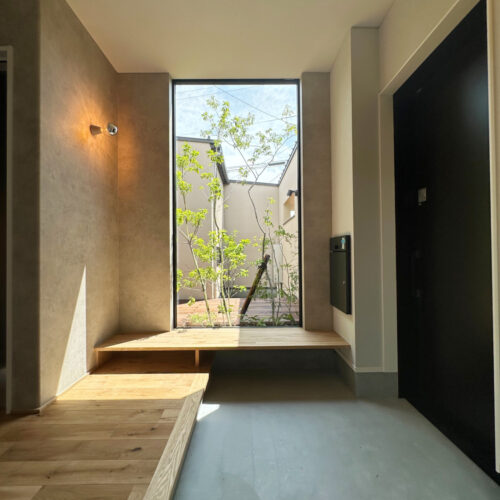 玄関には造作ベンチを！ちょっと腰掛ければ靴の着脱がしやすかったり、外出時の荷物や買い物した荷物を一時的に置いたりと様々な使い方で活躍しそうなベンチです。大きな窓から入る外の光が玄関内を明るく照らしてくれます。