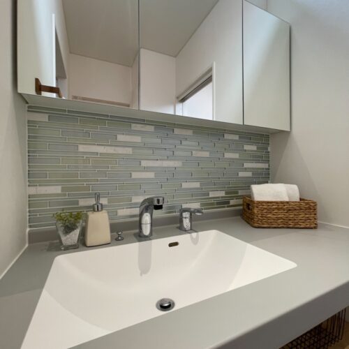 ガラスタイルがとってもオシャレな洗面所☆  アイカ工業さんの指紋が目立ちにくくマットな質感の洗面台で、お掃除もあっという間に終わります。  三面鏡の後ろは収納になっています。