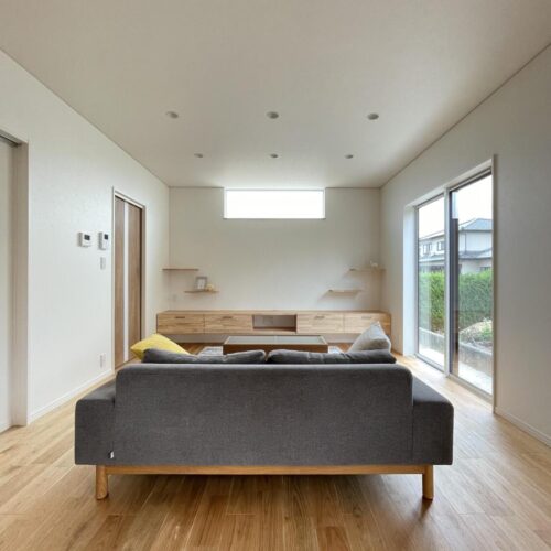 玄関ホールは、サイズオーダーした横長のFIX窓。造作棚は郵便物を受ける棚として、空間を演出する棚として使います。建具の取手の色に合わせ、造作棚の金物も“黒”にしました。