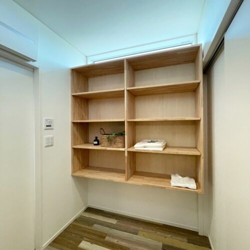 サンルームの横ある脱衣室。  フロアタイルはサンルームから続いて同じものを。（フロアタイル：サンゲツ WD-1106）  タオルなどを収納できる造作棚は、可動棚になっています。