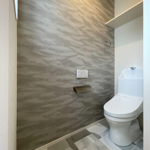 2階トイレは手洗付きのシンプルなものを。  波や水の揺らぎを濃淡のパールを重ねて表現し、なじみのよいニュアンスカラーでシアーな印象に仕上げられたリリカラの波模様のクロスです。