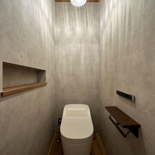 グレーのクロスで囲まれたオシャレなトイレ空間。  トイレには窓を設けず、照明で遊ぶという選択に☆彡