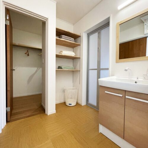 洗面脱衣室はサンルームとファミリークローゼットと繋がっています。乾いたタオルやパジャマはお風呂の入り口横にある棚へ収納。左奥に見える入り口がファミリークローゼットへの入り口です。