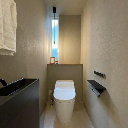 グレーベースで落ち着きのあるトイレ空間。手洗い場やペーパーホルダー、タオル掛けなどはブラックで統一されました。色のまとまりがすごく落ち着いていて片隅に添えたペンダントライトでより柔らかい雰囲気の空間に（＾－＾）