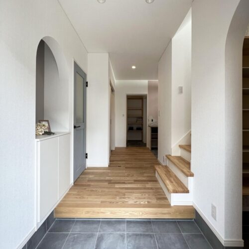 玄関に入ると二つのアーチ壁がお出迎え♡カワイイ～(*^^*)  床材は力強い木目が特徴のナラをチョイス！真っ白の壁との相性もバッチリ♪  奥行きがある玄関ホールで圧迫感を感じません(*^^)v     床材：無垢フローリング ナラ材  クロス：サンゲツ 77-2001