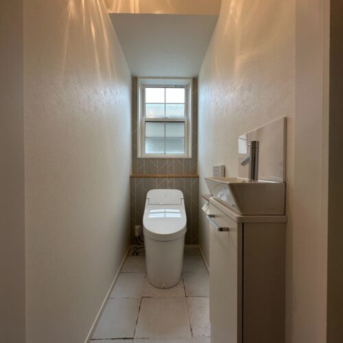 階段下の空間を利用したトイレ。ヴィンテージ風のフロアタイルに陰影が綺麗な照明を組み合わせました。