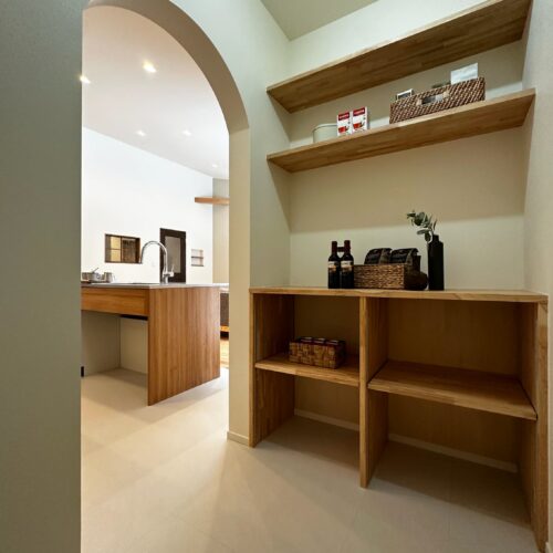 キッチンのすぐ隣には、アーチの入口のパントリーを造りました。造作棚の向かい側に冷蔵庫置き場を設け、リビングから生活感が見えにくい配置にしています。