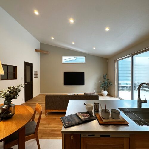 テレビ側の壁には、アクセントとしてグレーのクロスを採用。 大きな掃き出し窓とテレビ上部の高窓から光がたっぷり入り、明るく心地の良い空間に仕上がりました。